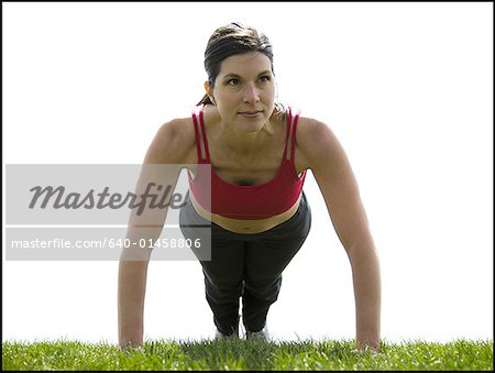 Woman doing pushups on grass outdoors