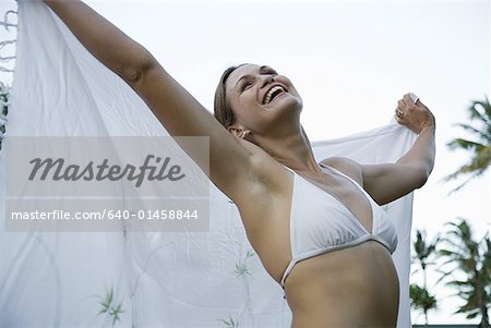 Femme en bikini avec une pellicule souriant avec les bras vers le haut à l'extérieur