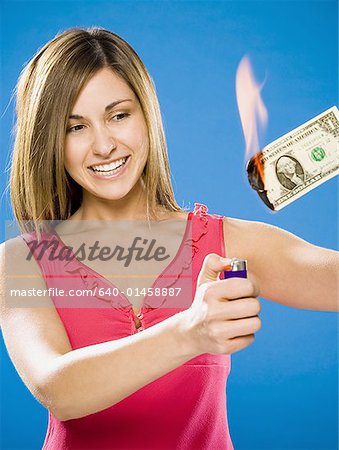 Woman setting American one dollar bill on fire