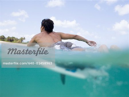 Man lying on surfboard in water