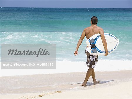 Homme avec planche de surf sur la plage