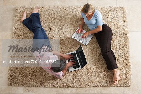Couple allongé sur le sol à l'aide d'ordinateurs portables
