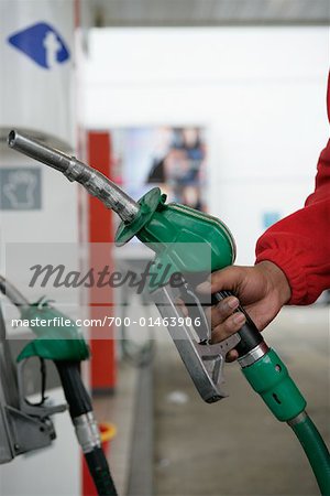 Man Holding Gasoline Pump at Gas Station