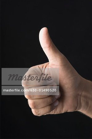 Close-up of a man's hand showing thumbs up sign