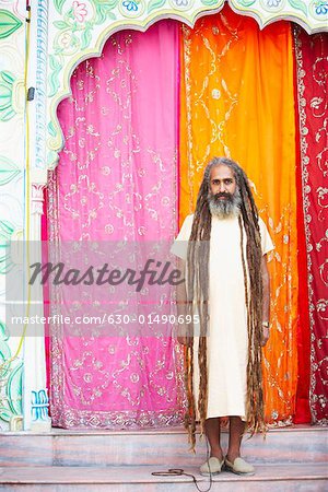 Portrait of a sadhu standing in front of a gate