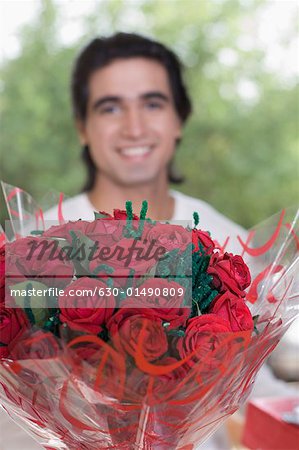 Close-up of a bouquet of flowers with a young man smiling in the background