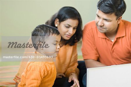 Close-up of a boy sitting in front of a laptop with his parents
