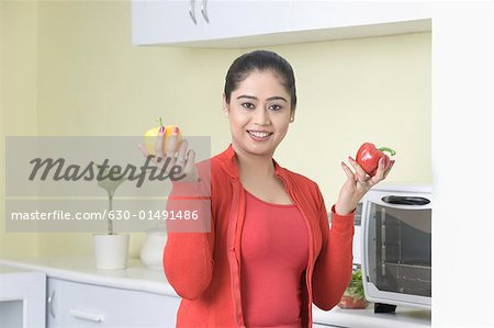 Portrait of a young woman holding bell peppers and smiling