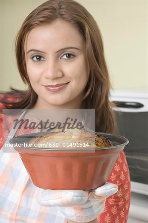 Portrait of a young woman holding a cake in a mould