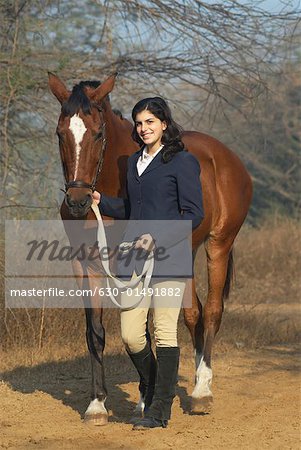 Portrait d'une adolescente qui marche avec un cheval et souriant