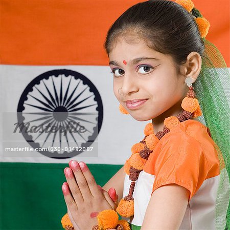 Portrait d'une jeune fille dans une position de prière devant un drapeau indien