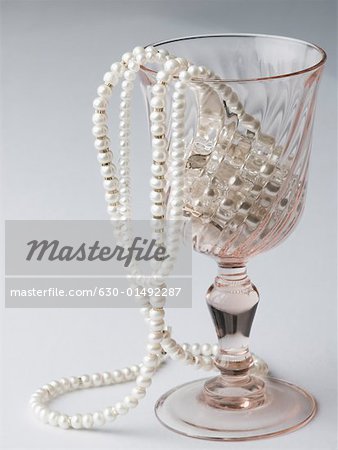 Gros plan des colliers de perles dans un verre à vin
