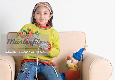 Portrait d'une jeune fille à genoux sur un fauteuil et jeu vidéo