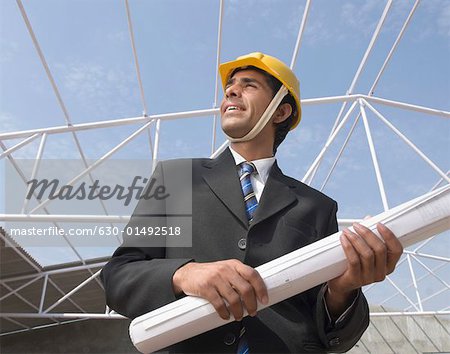 Low Angle View eines männlichen Architekten halten eine Blaupause auf einer Baustelle