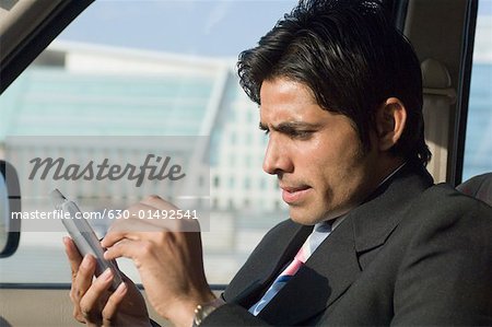 Close-up of a businessman using a personal data assistant in a car