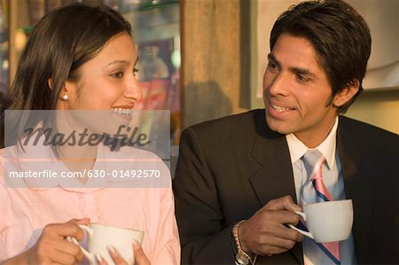 Homme d'affaires et une femme tenant des tasses à café et souriant