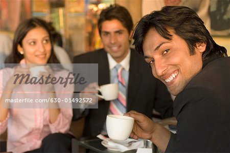 Deux hommes d'affaires et une femme tenant des tasses à café