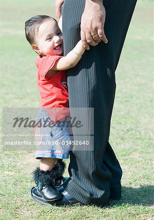 Side profile of a baby girl standing on her father's feet