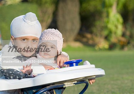 Portrait d'un garçon avec sa sœur assis dans une marchette pour bébé