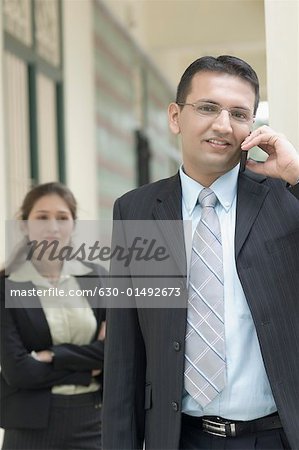 Porträt eines Kaufmanns im Gespräch mit einer geschäftsfrau, die hinter ihm stehen auf einem Mobiltelefon