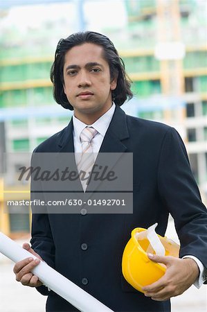 Portrait of a businessman holding a blueprint and a hardhat
