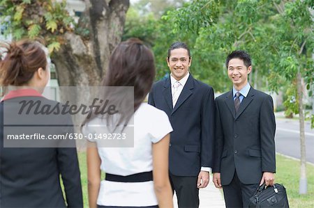 Two businessmen looking at two businesswomen