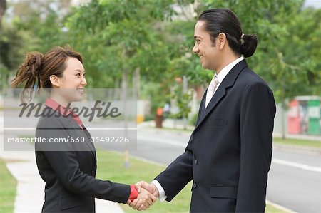 Seitenansicht eines Kaufmanns und einer geschäftsfrau Händeschütteln und lächelnd