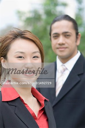 Porträt einer geschäftsfrau mit einem Geschäftsmann, der neben ihr Stand lächelnd