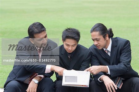 Trois hommes d'affaires en regardant un magazine