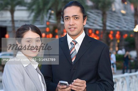 Portrait d'un homme d'affaires détenant un assistant personnel avec une femme d'affaires à côté de lui