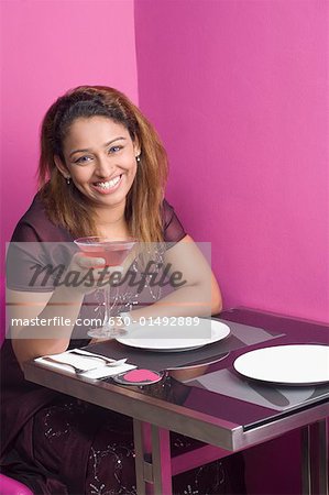 Portrait d'une jeune femme assise dans un restaurant et tenant un martini
