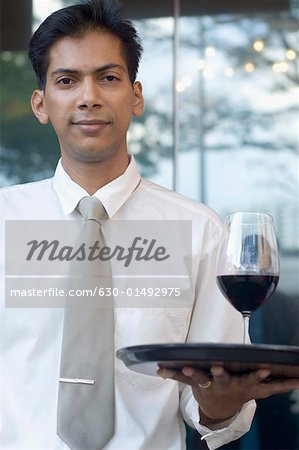 Portrait of a mid adult man holding a glass of red wine on a tray