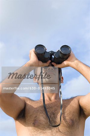 Low angle view of a young man looking through a pair of binoculars