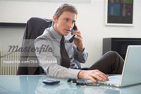 Businessman Talking on Phone, Using Laptop Computer