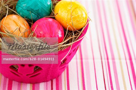 Nest made of straw with eggs in a basket, close-up