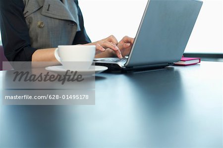 Businesswoman using a laptop, cup of coffee in foreground