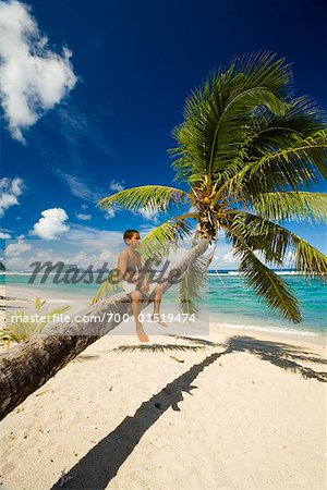 Junge sitzt auf Palm Tree Trunk, Faofao Beach, Upolu, Samoa