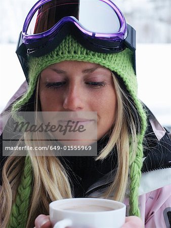 Young woman in ski-wear with cup of hot chocolate, close-up, portrait
