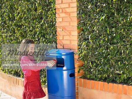 Young girl (5-7) putting can in public bin, Alicante, Spain,