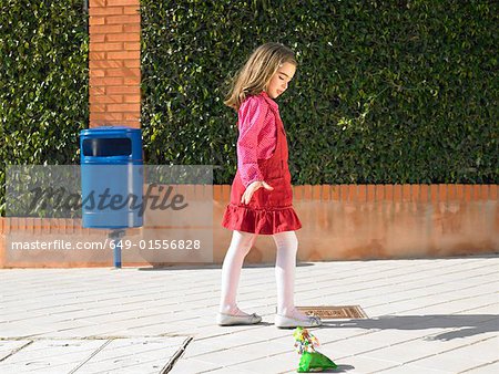 Young girl (5-7) dropping litter on pavement next to public bin, Alicante, Spain,