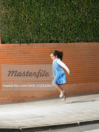 Little girl skipping down pavement, Alicante, Spain,