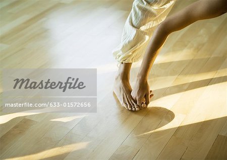 Woman doing prasarita padottanasana posture, cropped view of leg and arm