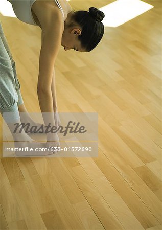 Woman doing standing forward bend, partial view