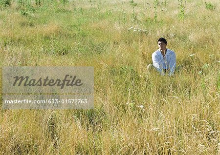 Mann sitzt im Feld, Augen geschlossen