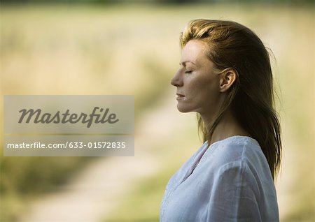 Woman outdoors with eyes closed, head and shoulders, profile