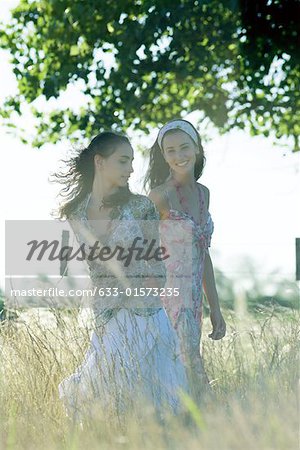Young women walking through field