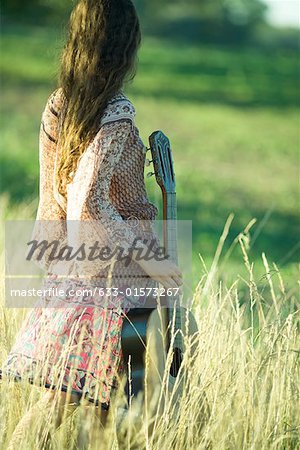 Hippie jungen Frau stehen im Feld, Betriebs-Gitarre, Rückansicht