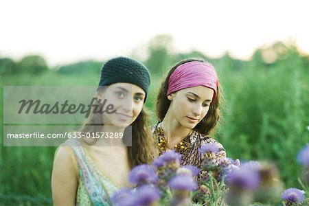 Young women standing in field, thistle in foreground
