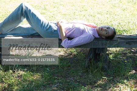 Businesswoman lying on bench, outdoors