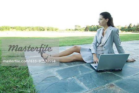 Businesswoman sitting on patio with laZSop, looking away